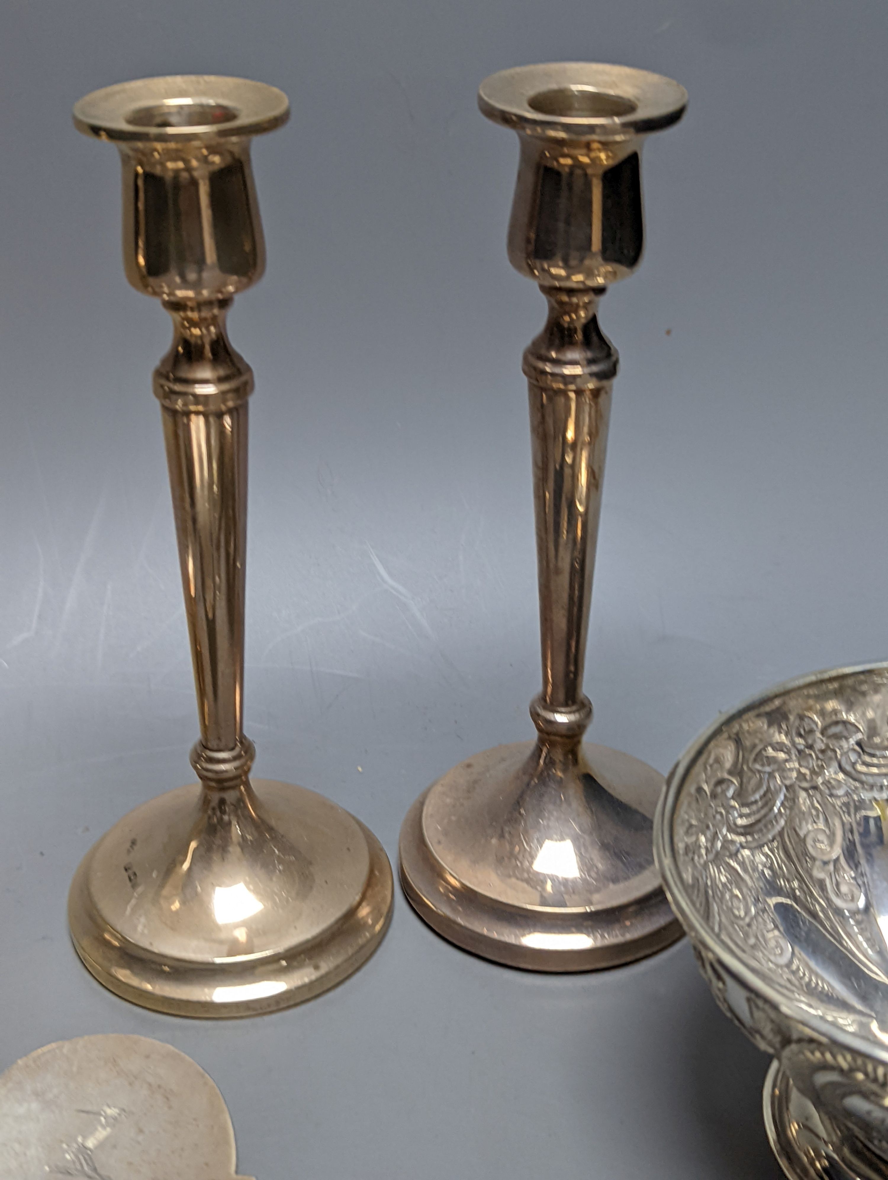 A mixed collection of silver to include a George III silver butter shell, London, 1799, a small cigarette box, two casters, a pair of slender candlesticks (loaded) and two small bowls including white metal